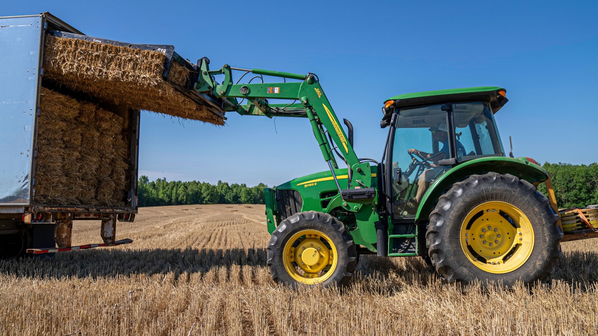 Tractor loading hay into a truck